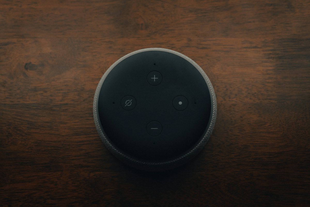 An Amazon Echo Dot seen from above on a wooden table